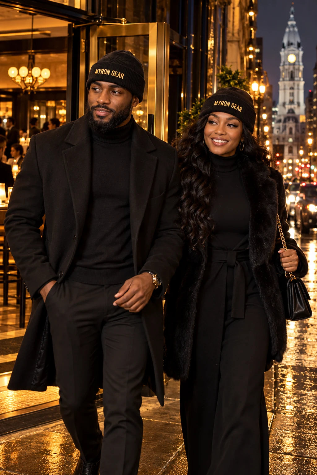 Two models wearing MYRON GEAR beanies on a city street at night